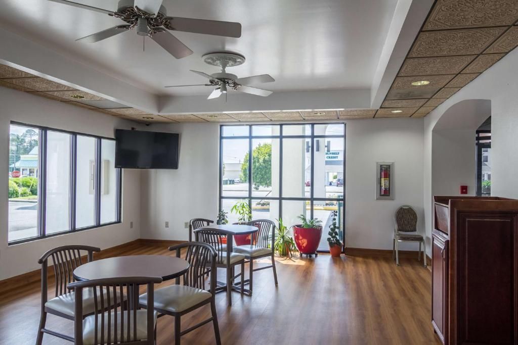 A spacious room with a high ceiling, large windows, and a ceiling fan.