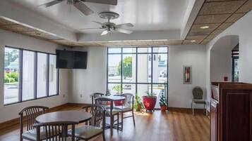 A spacious room with a high ceiling, large windows, and a ceiling fan.