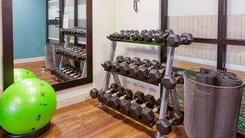 A gym with a mirror, a rack of dumbbells, and exercise balls.