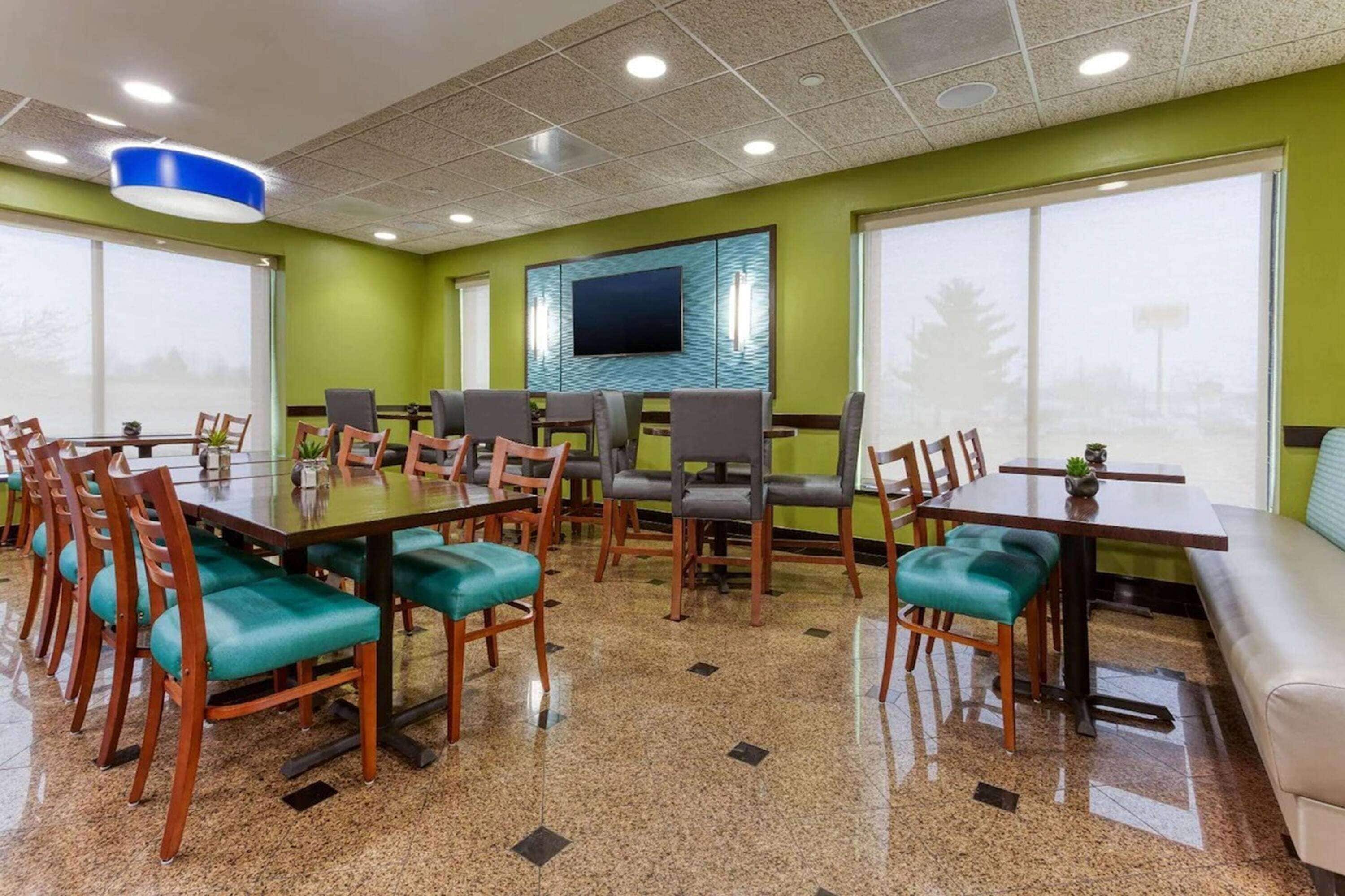 A conference room with a large table, multiple chairs, a television, and large windows.