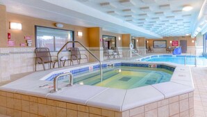 A hotel indoor pool area with a hot tub, seating, and a view of the outdoors. - Heritage Inn & Suites St. Louis/Fenton, Trademark by Wyndham (Fenton)