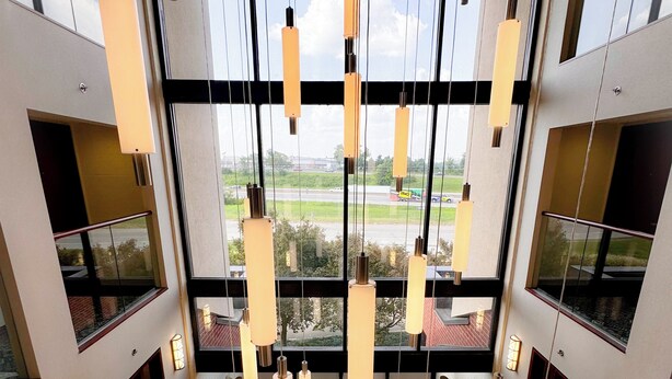 A modern interior with hanging pendant lights, large windows, and a view of the outside. - Heritage Inn & Suites St. Louis/Fenton, Trademark by Wyndham (Fenton)