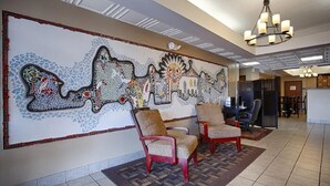 Un vestíbulo con una pared de mosaicos, dos sillones y una araña.