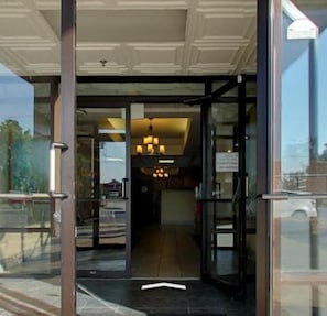 A hotel entrance with a glass door, a visible interior with a chandelier, and a sign indicating a parking area. - Econo Lodge (Waynesboro)