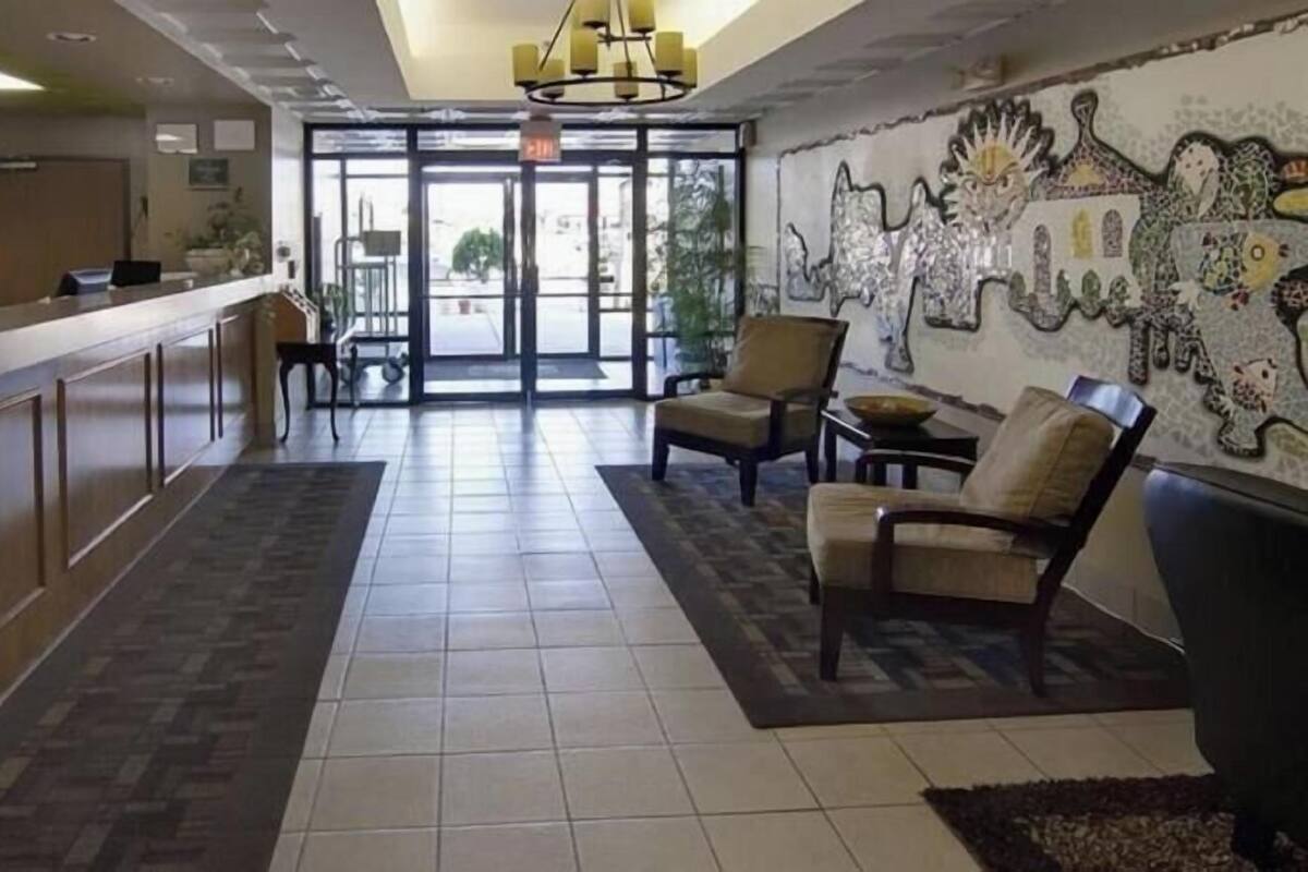 A hotel lobby with a reception desk, seating area, and a mosaic wall.