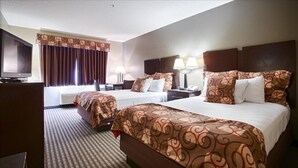 Habitación de hotel con dos camas, televisión y escritorio con lámpara.