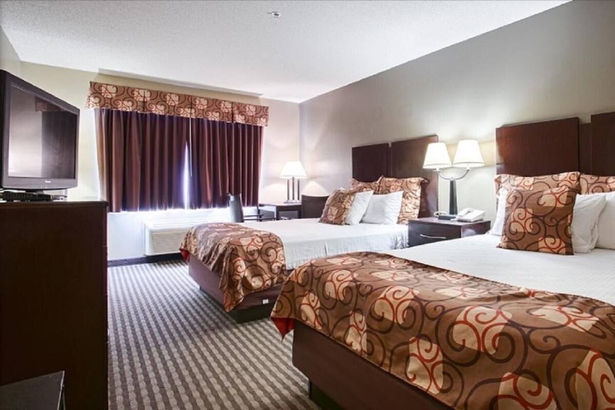 A hotel room with two beds, a TV, and a desk with a lamp.