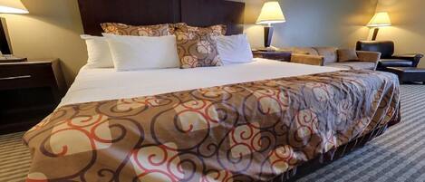 Una habitación de hotel con una cama grande, dos mesitas de noche, un escritorio y una silla.