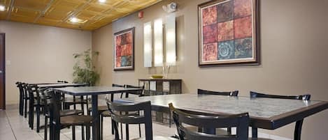 A conference room with multiple tables and chairs, a ceiling with a grid pattern, and artwork on the walls.