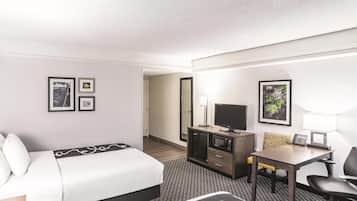 A hotel room with a bed, a desk, a chair, a television, and a small cabinet.