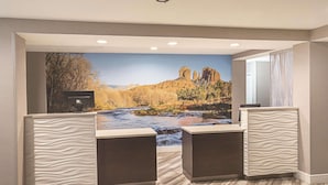 A hotel room with a large mural of a river and mountains, a desk with a computer, and a view of the outdoors.