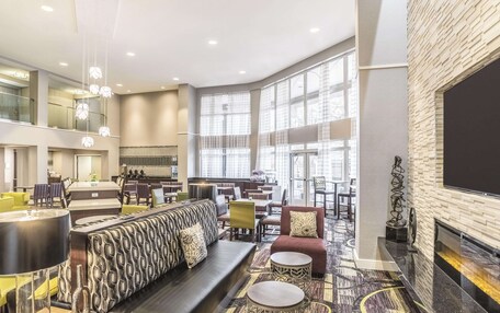 A spacious lobby with a high ceiling, large windows, a fireplace, and a variety of seating arrangements.