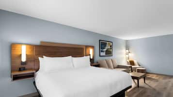A modern hotel room with a large bed, bedside tables, a desk, and a chair.