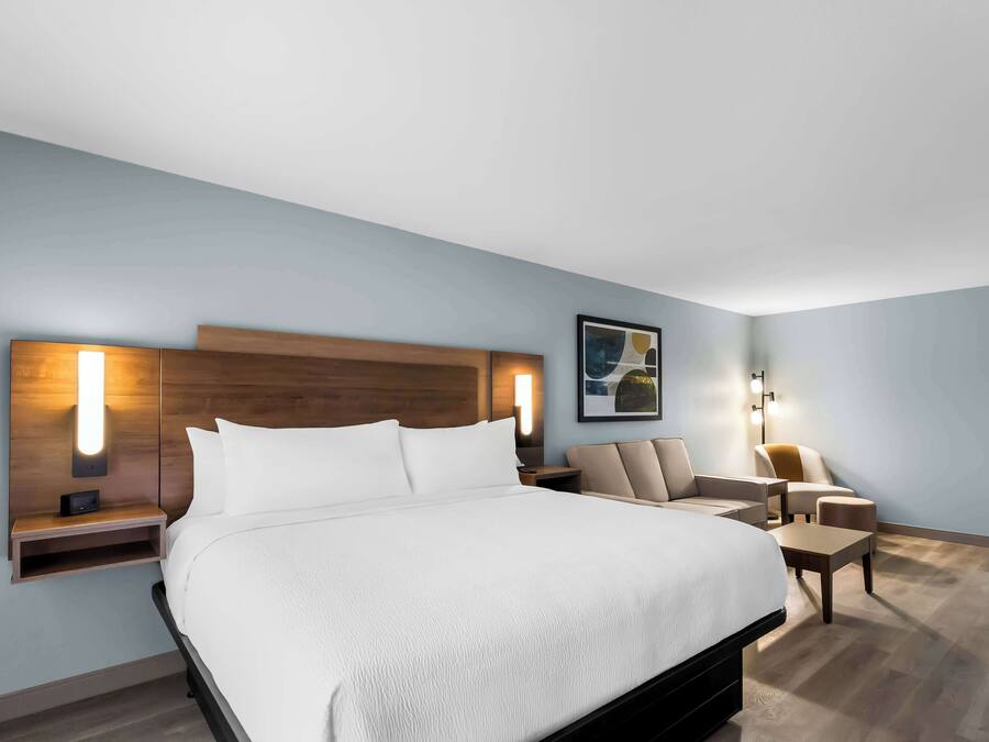 A modern hotel room with a large bed, bedside tables, a desk, and a chair.