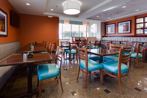 Un interior de restaurante con cabinas y mesas, sillas con cojines azules y cuadros en las paredes.