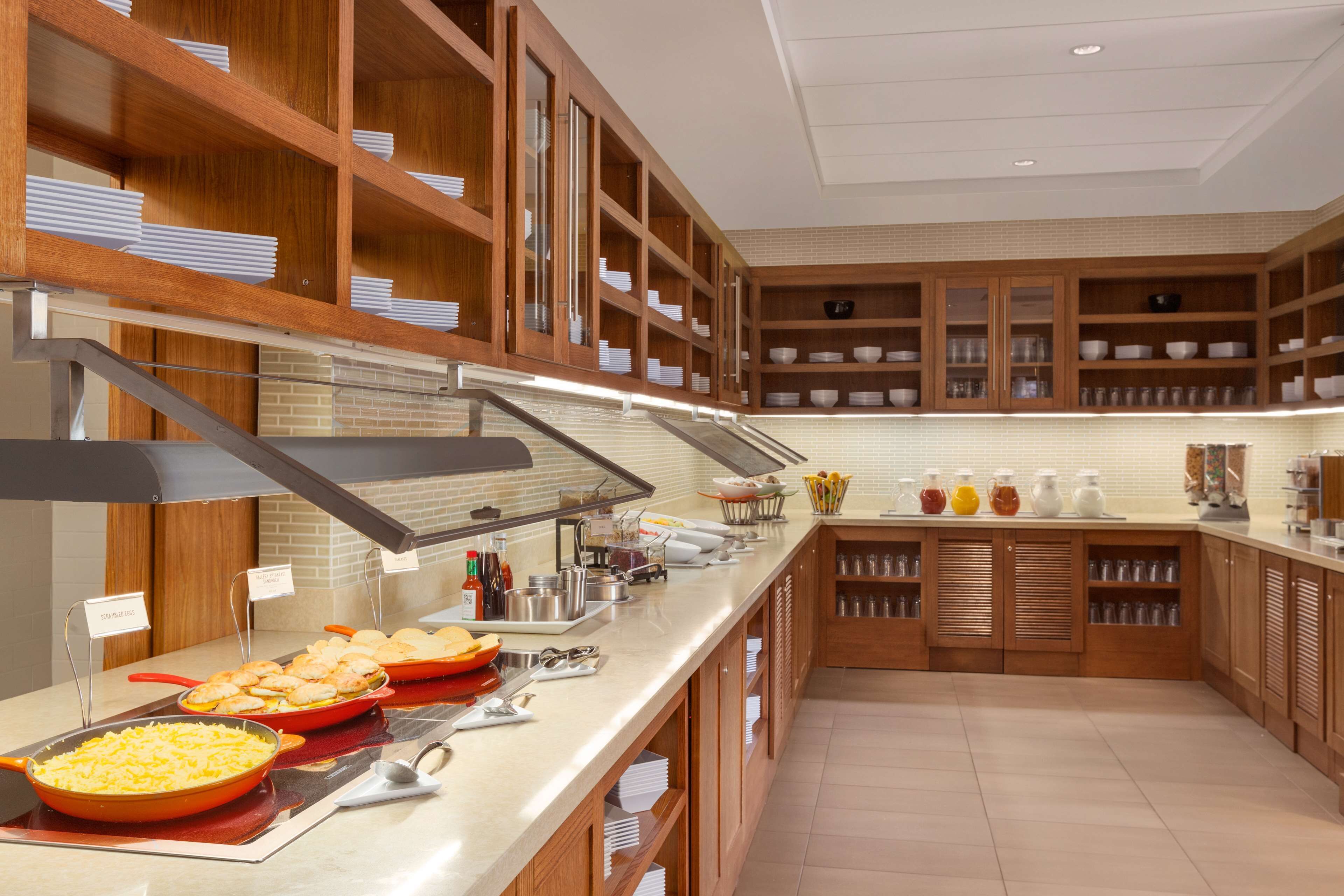 Un buffet avec une variété de plats et d’ustensiles, des armoires en bois et un mur recouvert de carreaux.