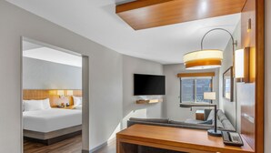 A hotel room with a bed, a desk with a chair, a flat-screen TV, a desk lamp, and a window with a view of buildings. - Hyatt Place Phoenix/Chandler-Fashion Center (Chandler)