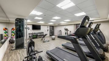 A gym with treadmills, exercise balls, dumbbells, and a mirrored wall.