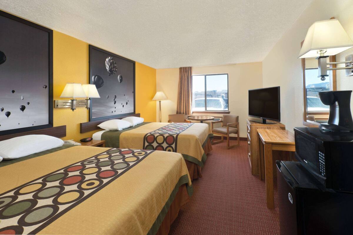 Une chambre d’hôtel avec deux lits, un bureau, une télévision et une fenêtre donnant sur un paysage agréable.