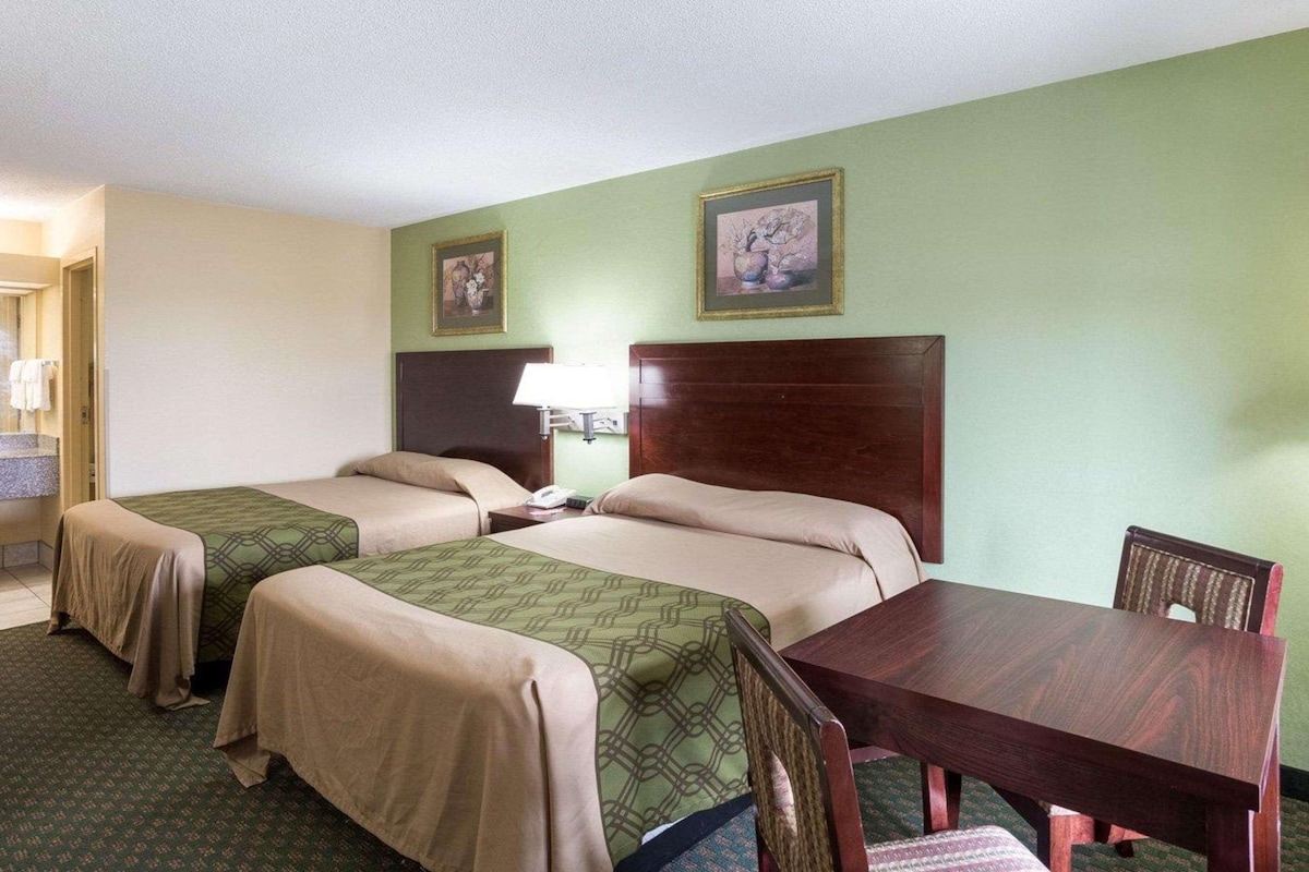 A hotel room with two beds, a desk, and a chair.