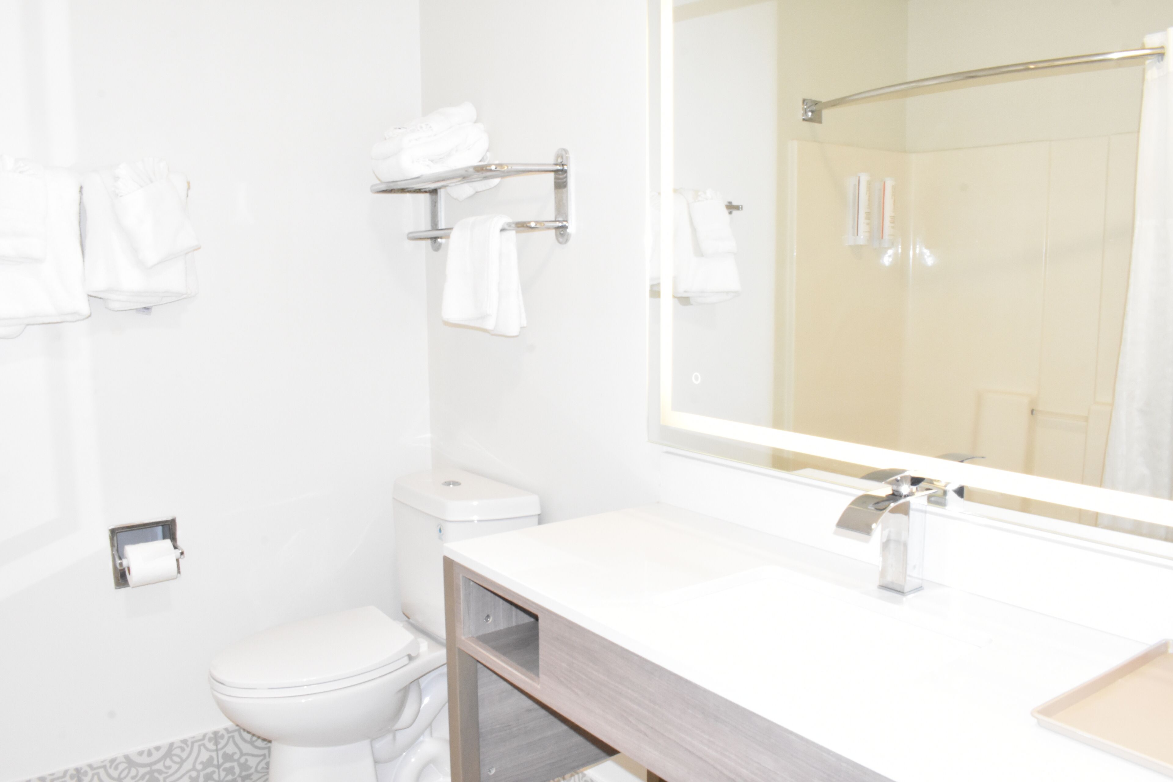 A modern bathroom with a white sink, a mirror, and a toilet.
