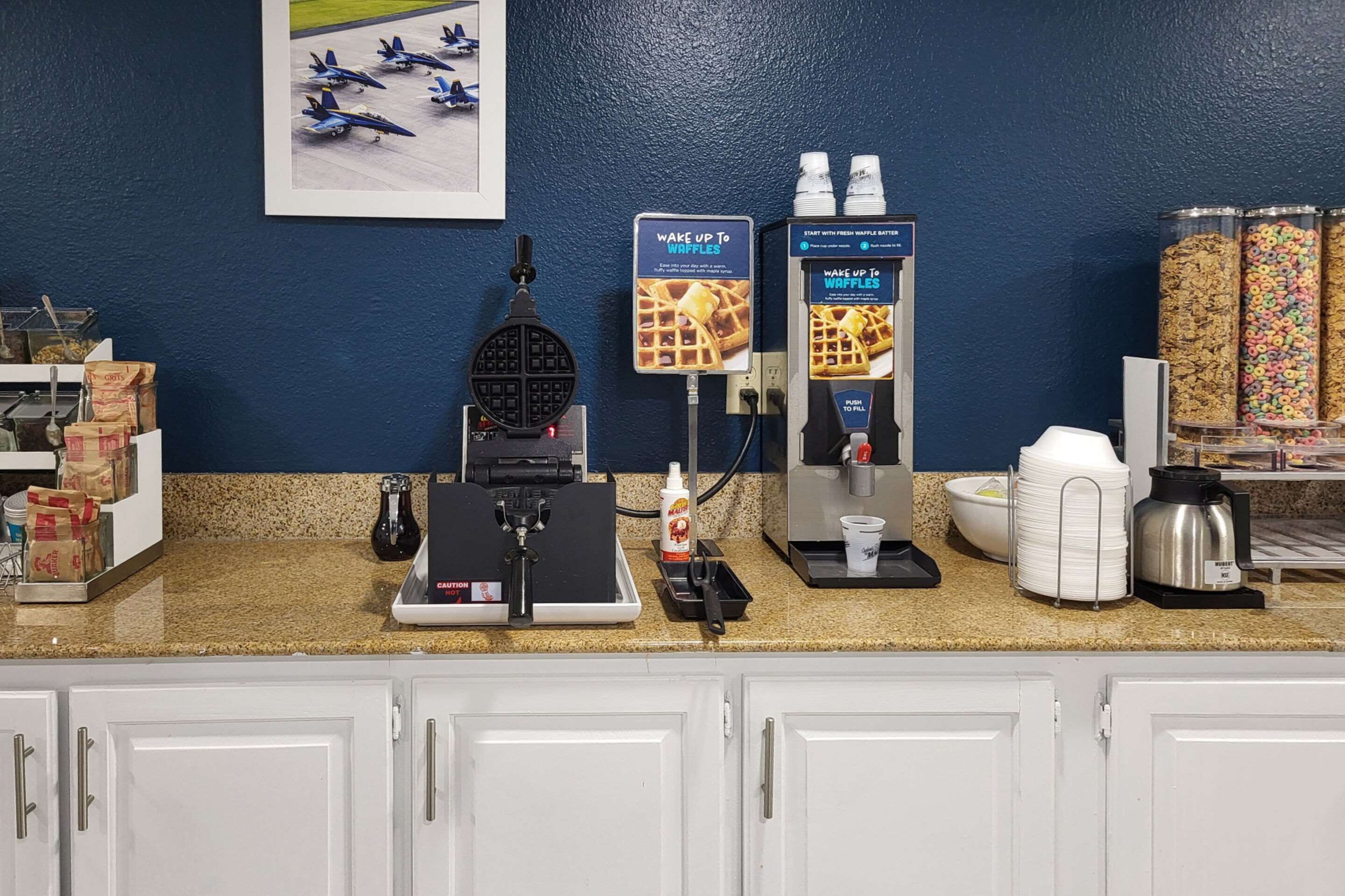 Una estación de desayuno con máquinas para hacer gofres, dispensadores de gofres y una máquina de café.