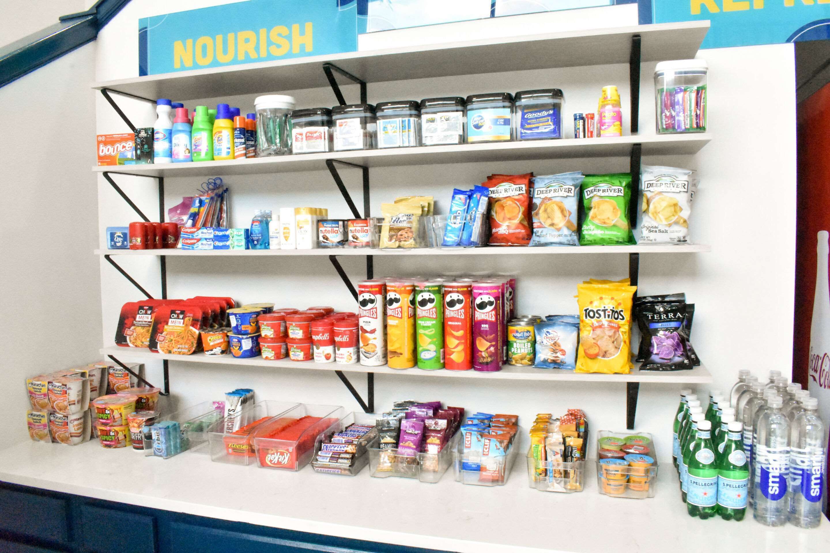 A shelf stocked with various food and drink items, including snacks, beverages, and condiments.