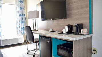 Una kitchenette moderna con televisión de pantalla plana, cafetera, microondas y un refrigerador pequeño.