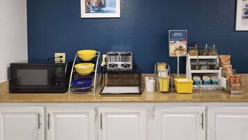 A kitchen area with a microwave, toaster, bowls, and a coffee station.