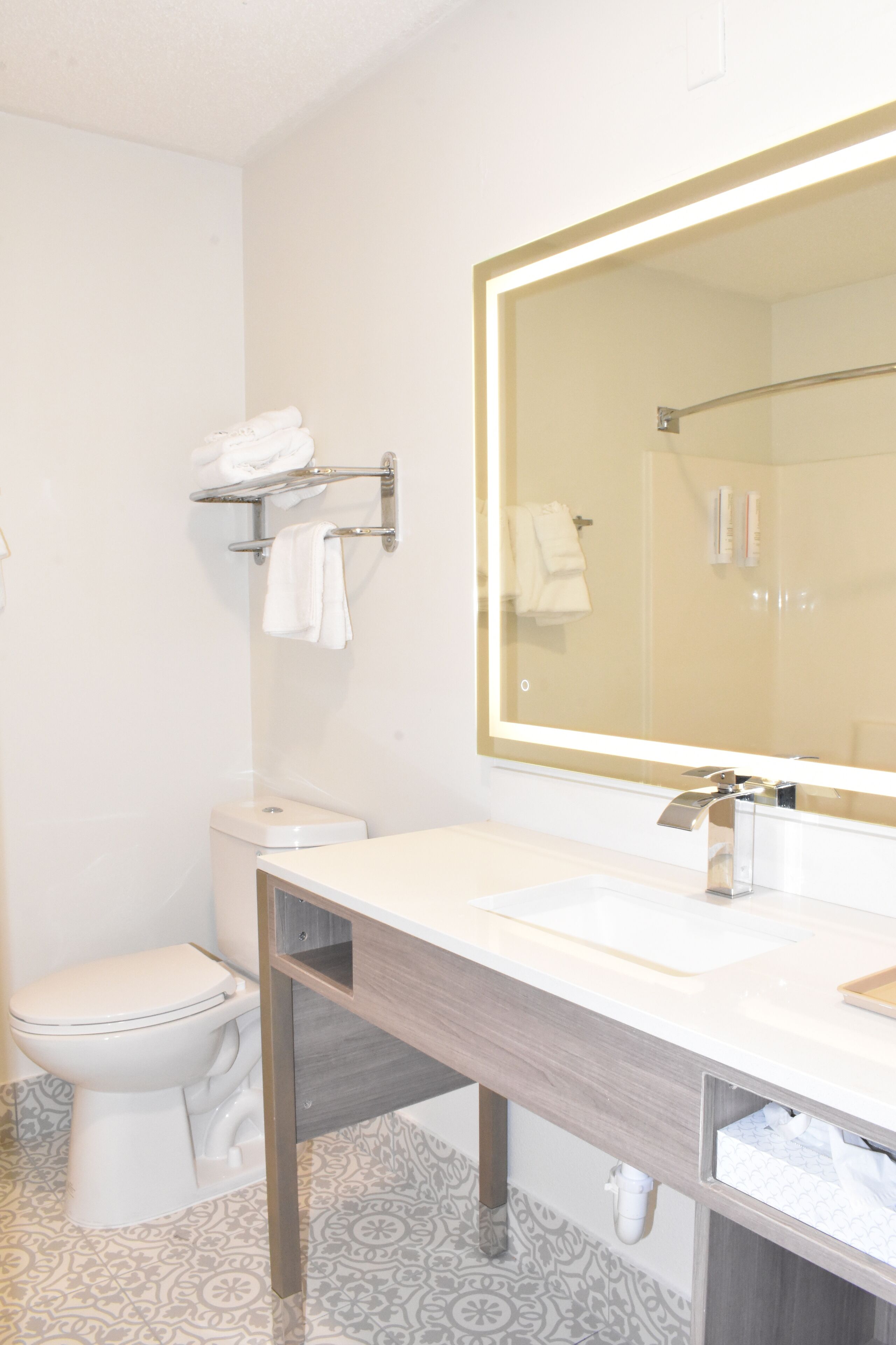 A bathroom with a toilet, sink, and mirror.