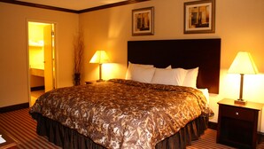 A hotel room with a large bed, two bedside tables with lamps, a headboard, and two framed pictures on the wall. - Rodeway Inn & Suites East Windsor (East Windsor)
