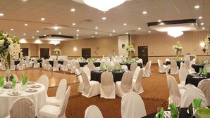 A banquet hall with round tables, white chairs, and floral centerpieces. - Rodeway Inn & Suites East Windsor (East Windsor)