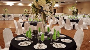 A banquet hall with round tables set for a formal event, each with white chairs and black tablecloths. - Rodeway Inn & Suites East Windsor (East Windsor)