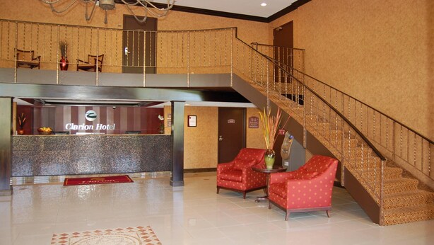 A hotel lobby with a reception desk, a staircase, and seating areas. - Rodeway Inn & Suites East Windsor (East Windsor)