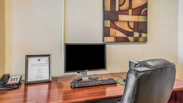 A desk with a computer, a phone, and a framed sign.
