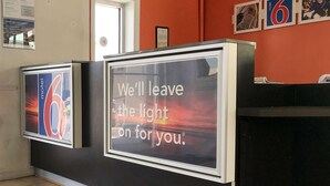 A motel reception desk with a sign stating "We'll leave the light on for you." - Motel 6 Tifton, GA (Tifton)