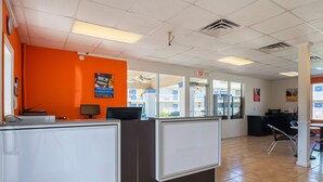 A reception area with a counter, a computer, and an exit sign. - Motel 6 Tifton, GA (Tifton)