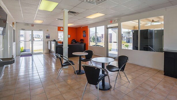 A spacious indoor area with tiled flooring, multiple seating arrangements including tables and chairs, and large windows providing natural light. - Motel 6 Tifton, GA (Tifton)