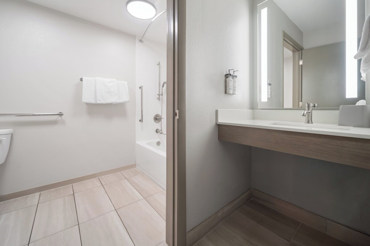 A modern bathroom with a bathtub, a toilet, a sink, and a mirror.