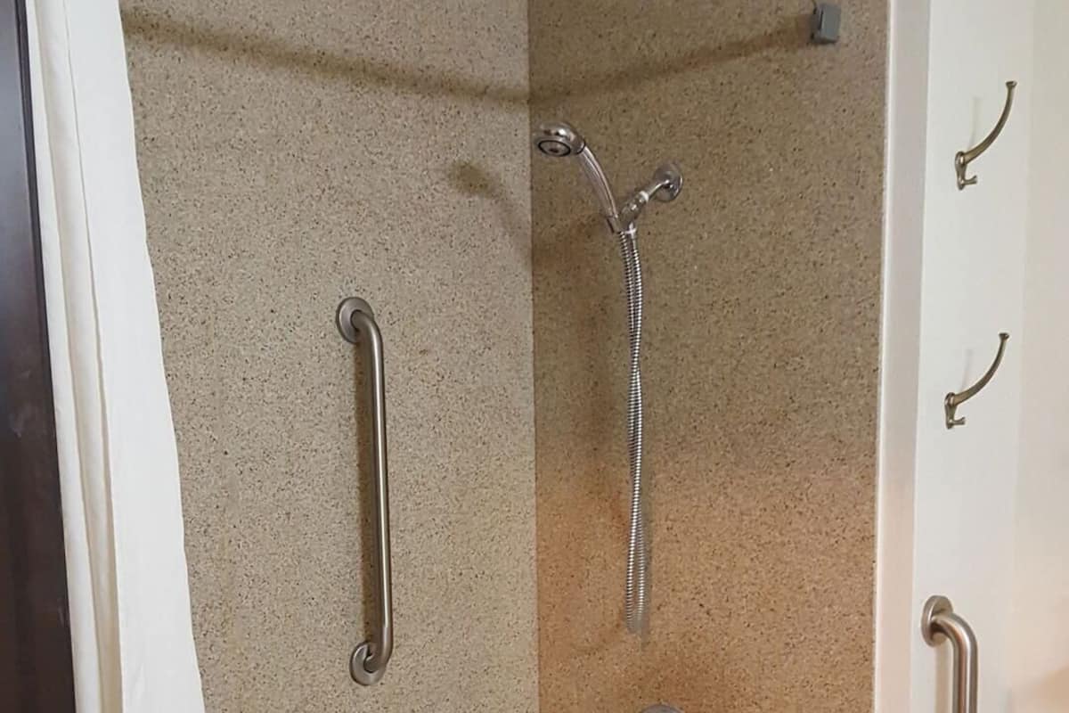 Ein Badezimmer mit einer Badewanne, einer Dusche und einer Haltestange.