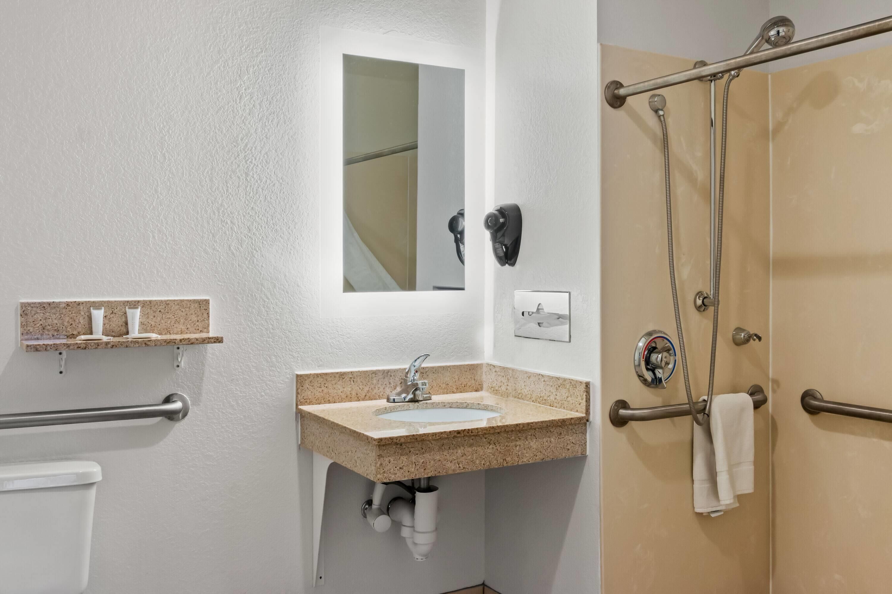Un baño con lavamanos, espejo, toallero y zona de ducha.