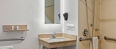 Un baño con lavamanos, espejo, toallero y zona de ducha.