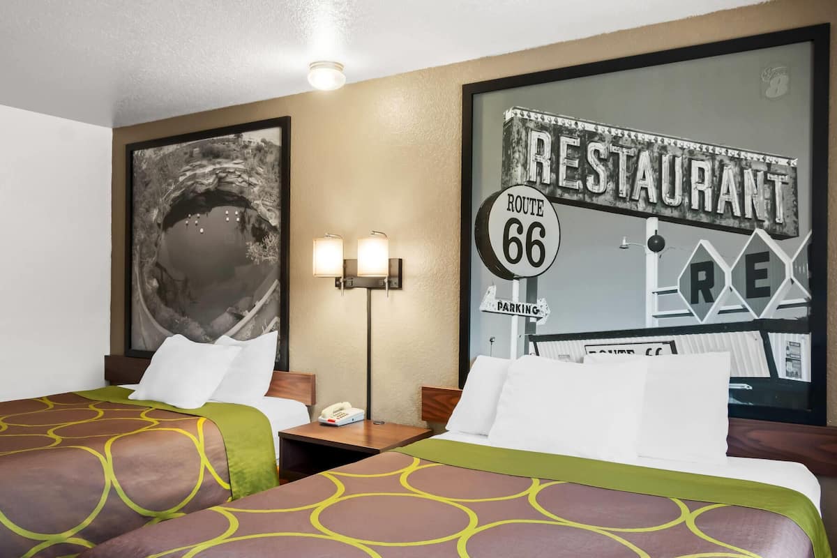 Ein Hotelzimmer mit zwei Betten, einem Nachttisch mit Telefon und einer Wand mit einem Schild eines Route 66 Restaurants.
