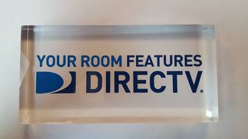 A clear acrylic sign with the text "YOUR ROOM FEATURES DIRECTV" and a logo.