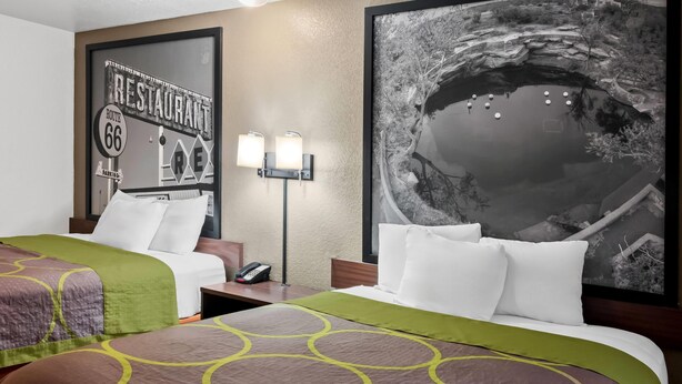 A hotel room with two beds, a large framed picture of a landscape, a sign for a restaurant, and a lamp.