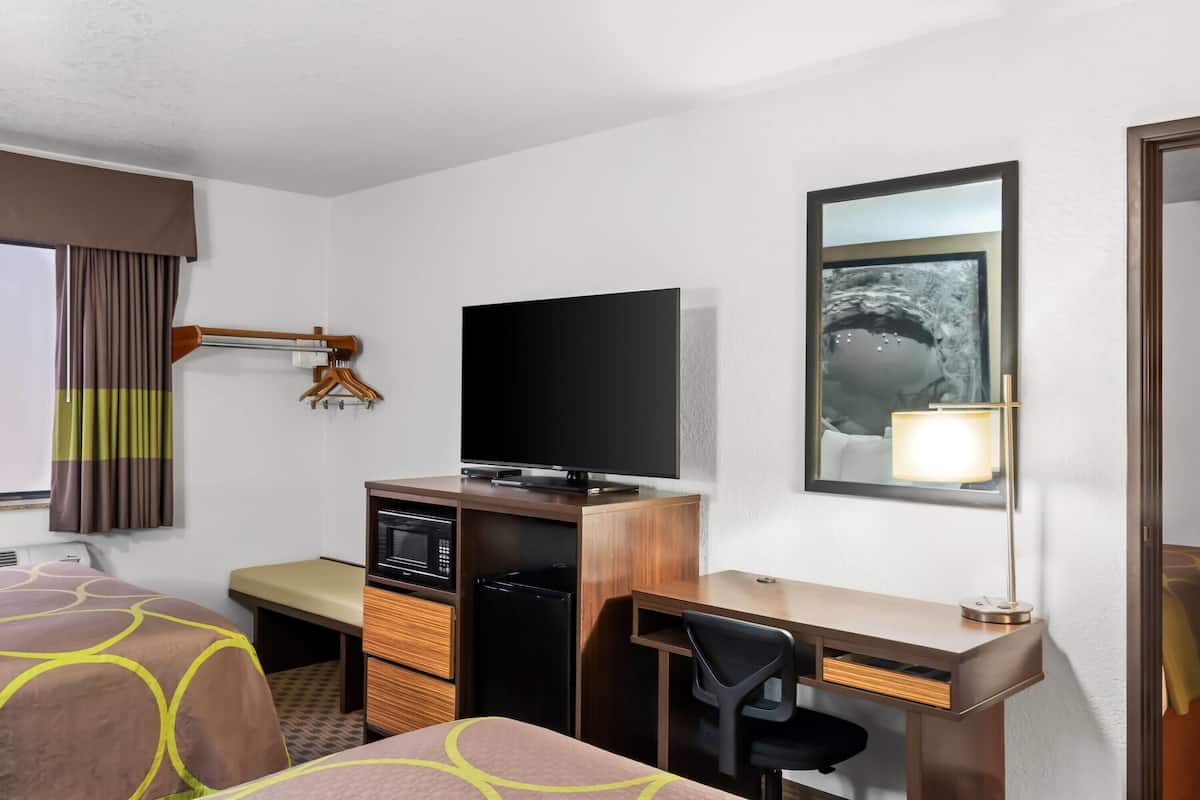 Ein Hotelzimmer mit Bett, Schreibtisch, Fernseher und Spiegel.