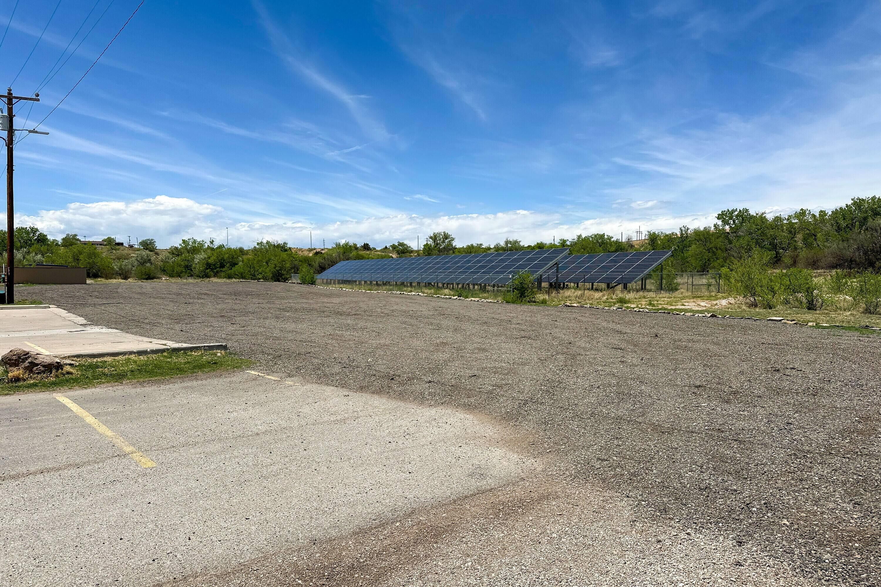 A parking lot with solar panels and a building in the background.