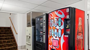 A vending machine area with Coca-Cola branded machines, a hand dryer, and a staircase.