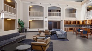 Eine großzügige Lobby mit grauem Sofa, Sesseln, einem Couchtisch und einem Bücherregal.