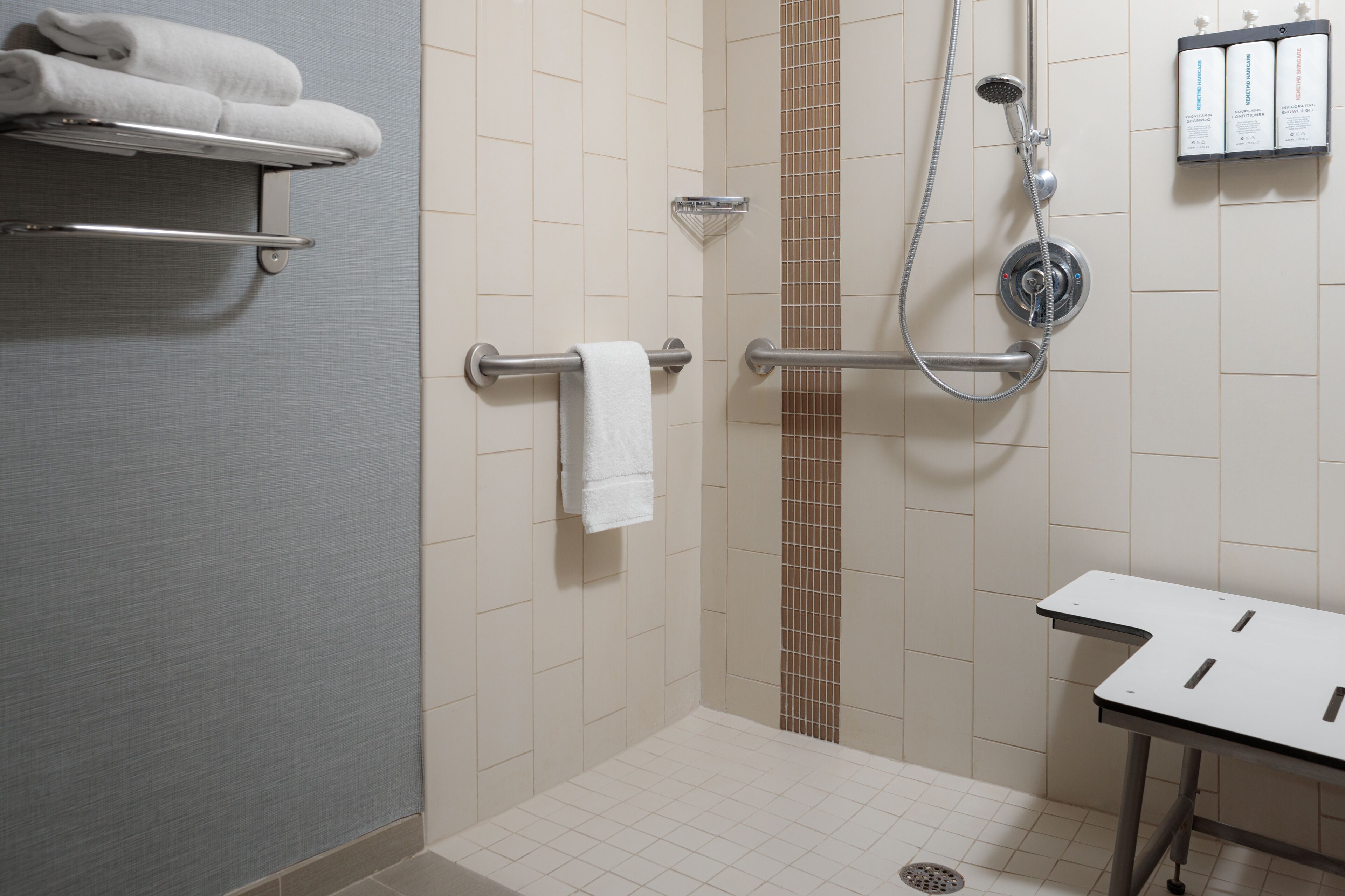 Une salle de bain avec une douche, un porte-serviettes et une étagère où sont rangées les serviettes.